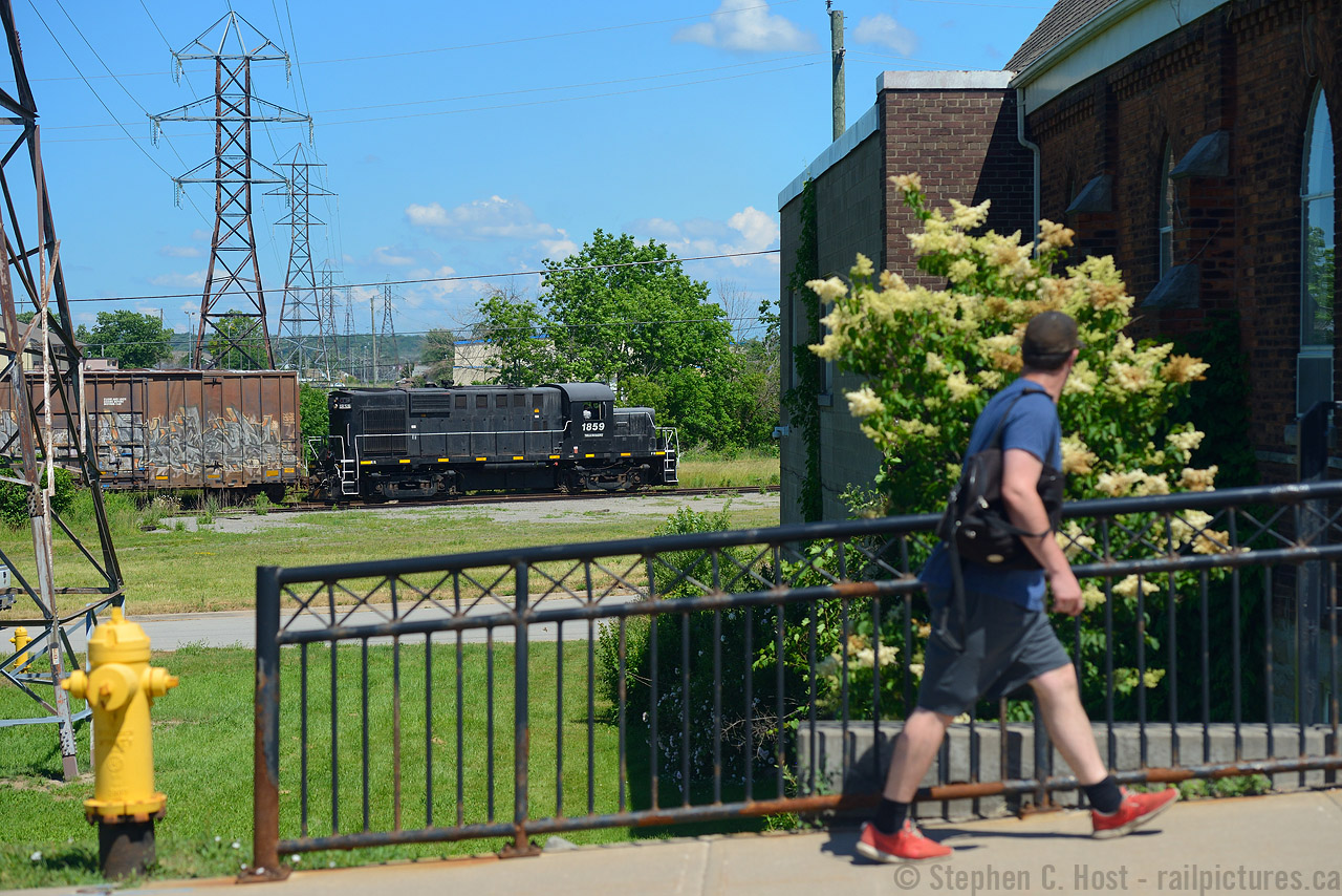 While Trillium's 1859 may be a black dip locomotive and rather lifeless in terms of it's paint scheme, it sure beats the leaser invasion that's coming around to most Shortlines as they replace older motive power. I'm dismayed to see more and more of them invading just about every shortline out there if you consider the numerous roads in the US. Many more are coming too.. so imagine my relief when I didn't see GMTX 333 and instead this old girl working in St. Catharines. I'm glad that the MLW's on Trillium are here to stay and the nasty rumours I heard late last year did not come to pass - railfan rumours can be vicious and I really only believe them when it actually happens. For the record, dropping by the shops over the weekend, Trillium has 1859, 108 and GMTX 333 in active service. Trillium 3582, which was seen in rotation in 2016 is now with the deadline with boarded up side windows. Curious, what happened to the ACR passenger cars that were stored on the line?
After finding this old girl I followed it and their crew to Merriton capturing standard photographs all along the way, but then this scene caught my eye, and I set up for a quick photo and this feller walking by actually took notice of the train. I'd like to think it's mostly a Railfan and young kid type thing, but there seems to be more train people out there than we give credit for.