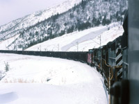 My view from pusher power assisting a south bound coal train "up the mountain" on a bleak winter afternoon.  If I recall, at the time most coal trains were 98 loads. We pushed on the caboose that had strengthen frames etc for coal service. The crew members would ride one of the pusher units instead of the caboose as per railway requirements for safety. The three SD40-2's that we had were in run 8 for most of the time grinding up the hill. It could get quite gassy and poor air in the Wolverine tunnel particularly if the leading power was diesels. If all the units were electric the air quality was good in the tunnel.