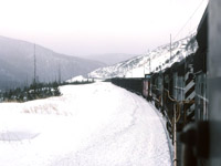 My view from pusher power assisting a south bound coal train "up the mountain" on a bleak winter afternoon. About center of the image you can see the train snaking through a rock cut, the lead power is beyond that point. If I recall, at the time most coal trains were 98 loads. We pushed on the caboose that had strengthen frames etc for coal service. The crew members would ride one of the pusher units instead of the caboose as per railway requirements for safety. The three SD40-2's that we had were in run 8 for most of the time grinding up the hill. It could get quite gassy and poor air in the Wolverine tunnel particularly if the leading power was diesels. If all the units were electric the air quality was good in the tunnel.