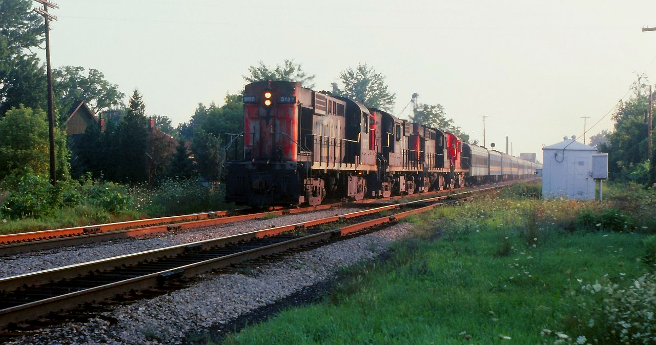 I had been in southern Ontario for a family function and went to Chatham to visit friends there. Being railfans we were out and about and got some slides of this eastbound passenger train leaving Chatham. This image is a "crop and zoom" and hopefully captures the scene. Four MLW's (3127-3108-3112-3121) were in charge moving this train. I am not sure of the train number, but, I'm sure Bruce Mercer would know as he was right beside me taking in this view.