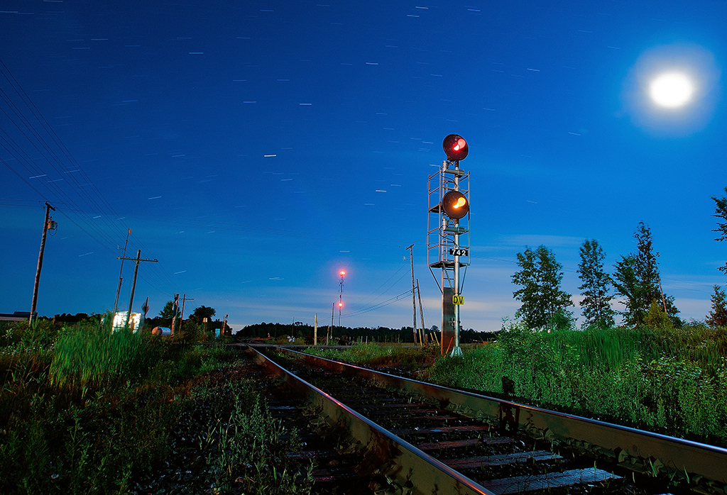It's a clear summer night and the RTC in Toronto has set up a meet at Brechin East with southward train Q102 taking the siding for northbound M329.