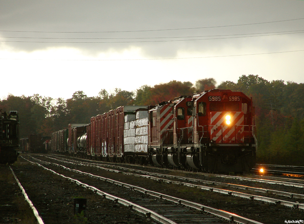It was a rainy evening in MacTier as CP 5985 North waits for a fresh crew to Cartier in track 2 with train 221 to Winnipeg. Before they depart they'll set off those 2 centerbeams into the North leg of the wye for the local Timber Mart to come unload, a service that has now disappeared along with the wye at MacTier and the locomotives pictured here.
