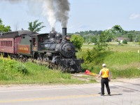 A crossing guard stands watch as the engineer of South Simcoe Railway 136 sounds the whistle. She is seen here crossing the 5th line, and heading south on the old Beeton Sub to Tottenham station to finish the day. 