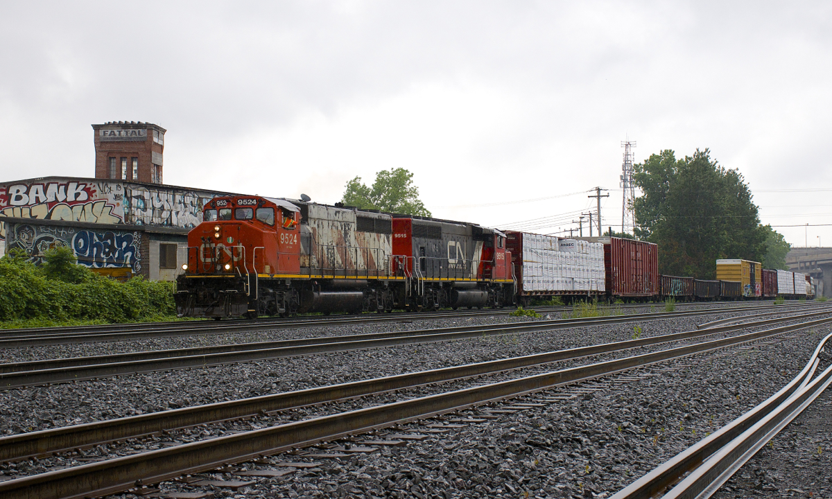 CN 324 has a pair of GP40-2L(W)'s in contrasting paint schemes (CN 9524 & CN 9515) as it heads through St-Henri on a rainy afternoon with a short train for the NECR in St. Albans, Vermont.
