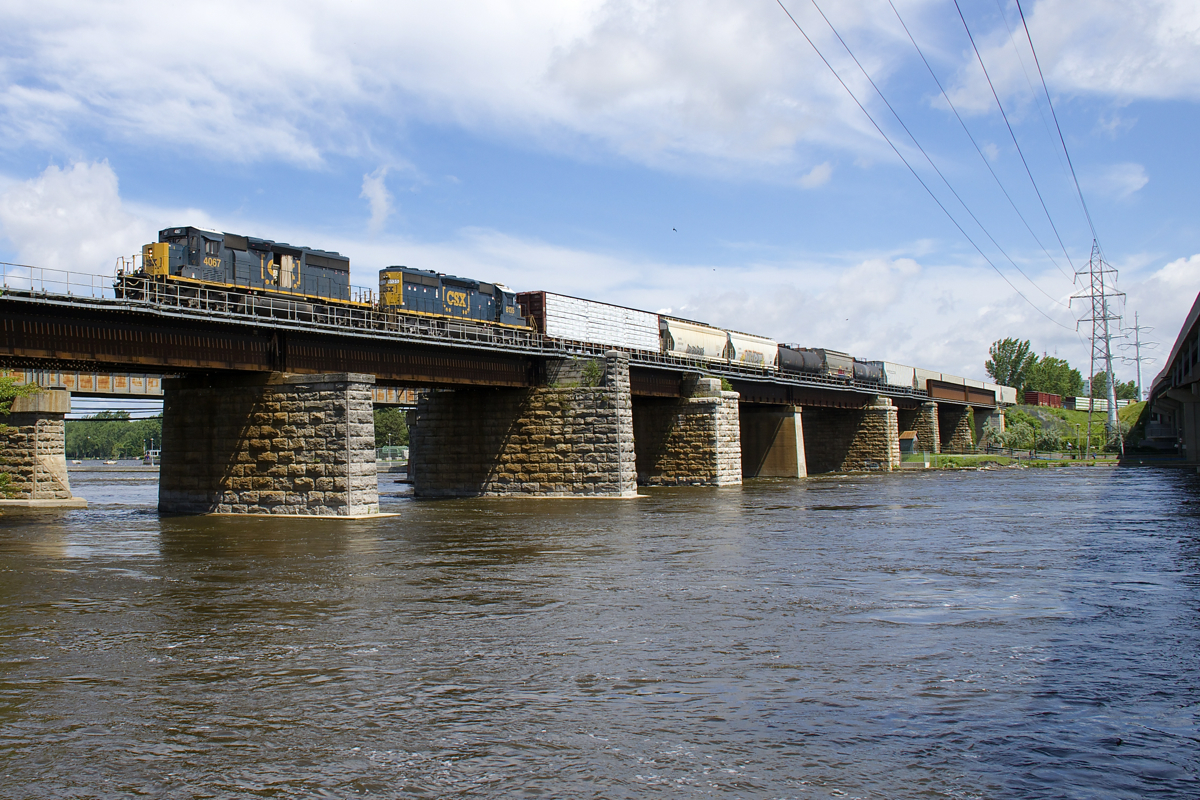 CN 327 is leaving the island of Montreal as it crosses the Ottawa River with a short train and a pair of EMD units for power. Lead unit CSXT 4067 is a rebuilt SD40-3 and was built as SD40-2 L&N 8110. Trailing is SD40-2 CSXT 8135, built as L&N 8135.