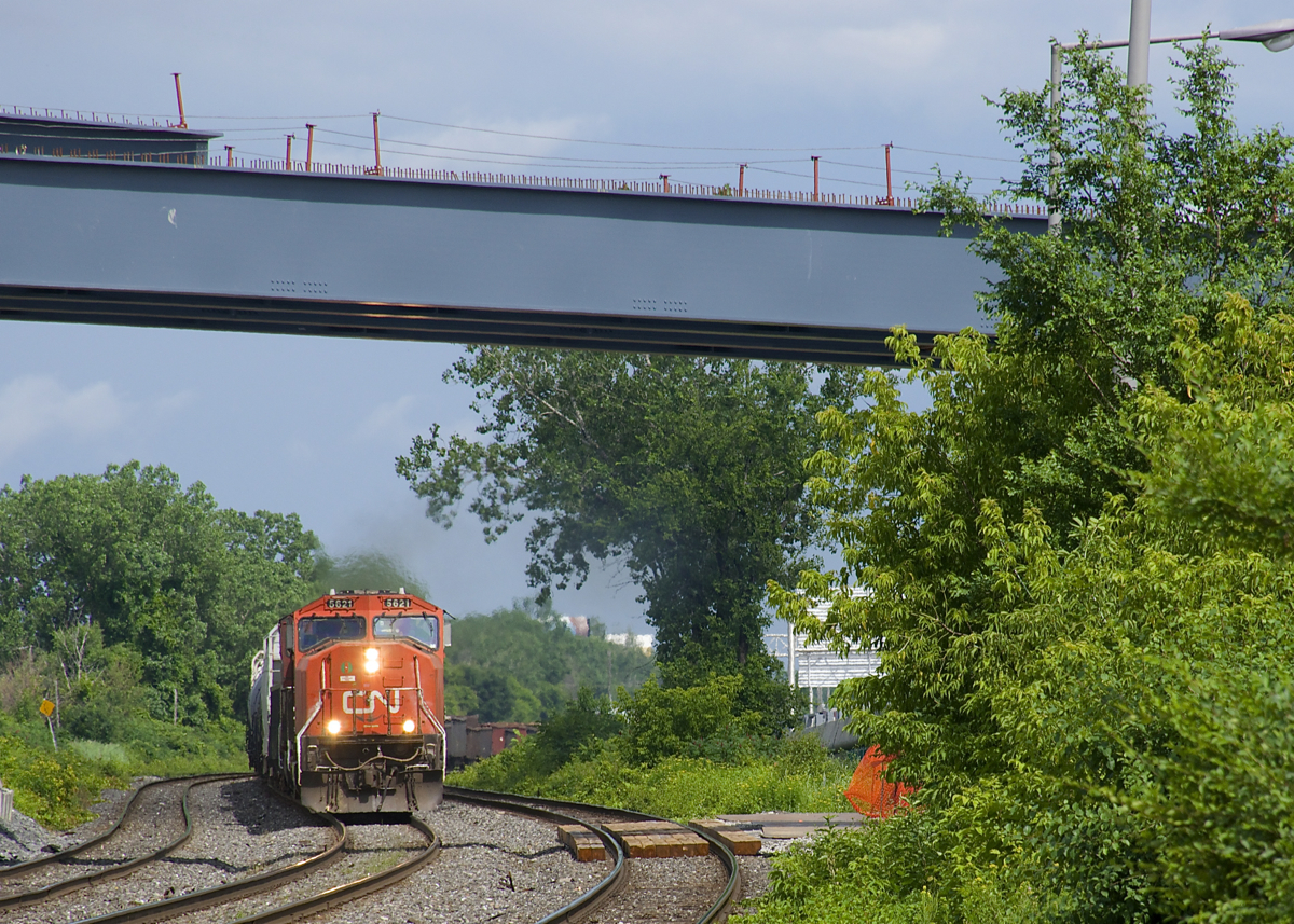 CN X321 has CN 5621 & CN 2646 for power and overflow traffic from Southwark Yard in St-Lambert as it approaches the VIA Rail Dorval Station not too long after the sun came out after a quick downpour. Above is a new overpass over the CN and CP tracks here, not yet completed.