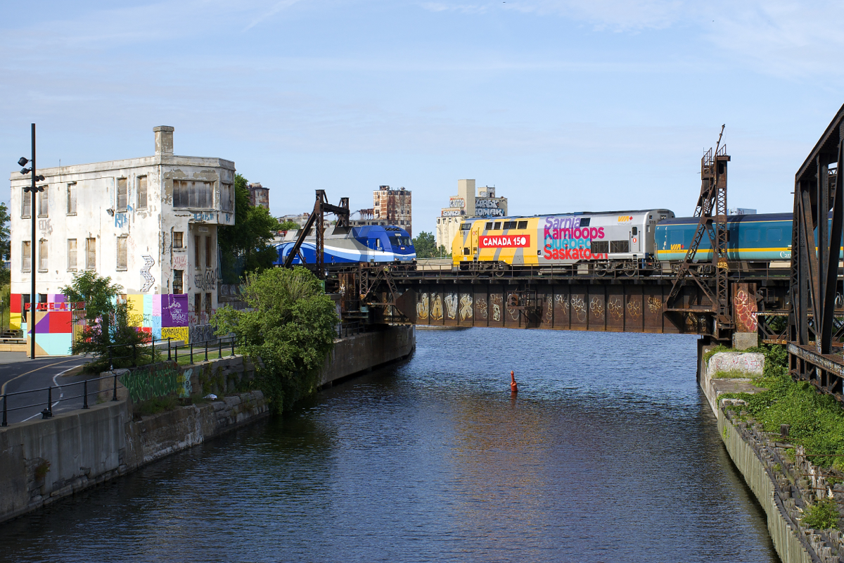 Both AMT 814 and VIA 37 have just left Central Station in Montreal as they cross the Lachine Canal. AMT 1357 is leading AMT 814, which is heading to Mont-Saint-Hilaire, while wrapped unit VIA 918 is shoving VIA 37, on its way to Fallowfield.