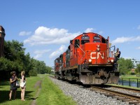 Two women stop and watch as CN 7083 & CN 7054 head light on the East Side Canal Bank Spur after dropping off eight cars at the Robin Hood Flour Mill (the last client on this line). At right is the Lachine Canal.