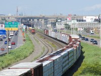 CN 527 and CN 324 are meeting near the soon to be demolished Turcot interchange in Montreal. CN 324 is heavily laden with export lumber bound for Vermont and interchange with the NECR.