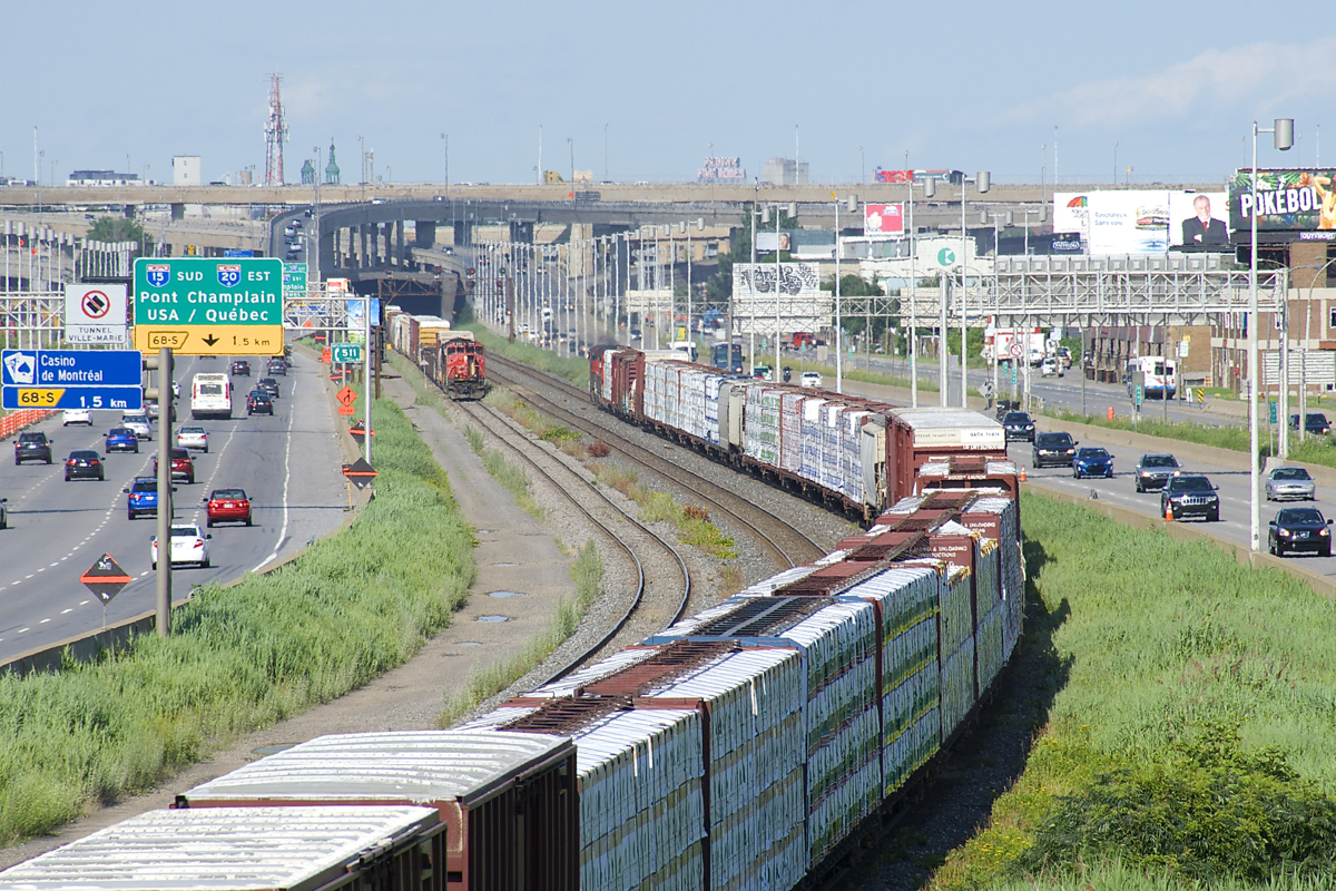 CN 527 and CN 324 are meeting near the soon to be demolished Turcot interchange in Montreal. CN 324 is heavily laden with export lumber bound for Vermont and interchange with the NECR.