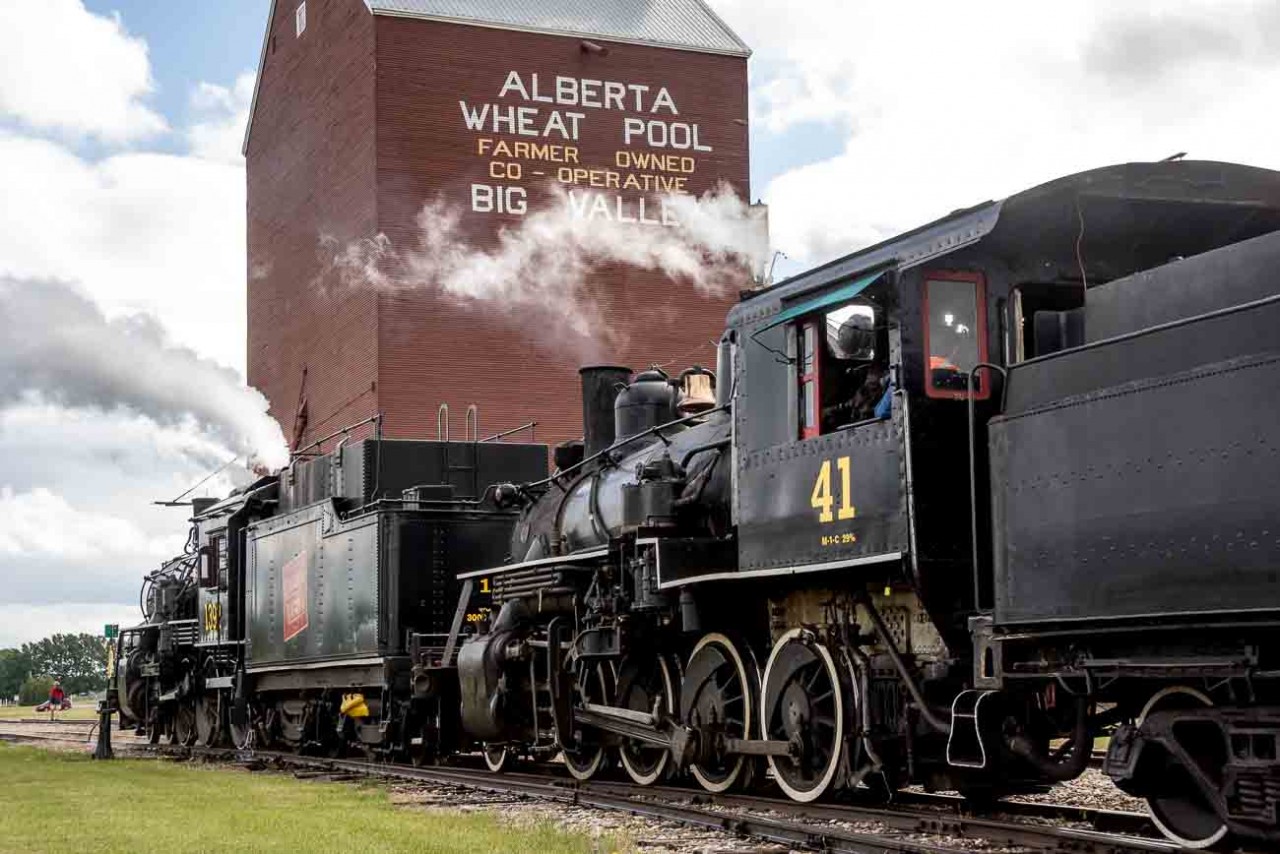 As a celebration of Canada's 150th anniversary as a nation, the Alberta Prairie Railway (APR) joined with the Alberta Railway Museum (AMR) in bringing their two steam locomotives together to run double-headed passenger trains between Stettler and Big Valley, Alberta for a week around Canada Day in 2017.  The locomotives involved are the APR 2-8-0 #41 ex-Mississippi Railway, and ARM 4-6-0 #1392 ex-Canadian National.  These photos show the activity on their many runs between these two centers.  In this image #1392 leads #41 to the water tank car before the restored grain elevator in the terminus town of Big Valley, Alberta.