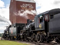 As a celebration of Canada's 150th anniversary as a nation, the Alberta Prairie Railway (APR) joined with the Alberta Railway Museum (AMR) in bringing their two steam locomotives together to run double-headed passenger trains between Stettler and Big Valley, Alberta for a week around Canada Day in 2017. The locomotives involved are the APR 2-8-0 #41 ex-Mississippi Railway, and ARM 4-6-0 #1392 ex-Canadian National. These photos show the activity on their many runs between these two centers. In this image #1392 leads #41 to the water tank car before the restored grain elevator in the terminus town of Big Valley, Alberta.