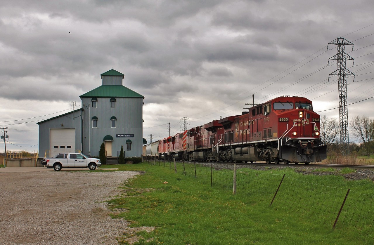 CP 141 with a pair of retired SD40-2F locomotives on their way to meet their maker, passes the old elevator in Elmstead, ON.