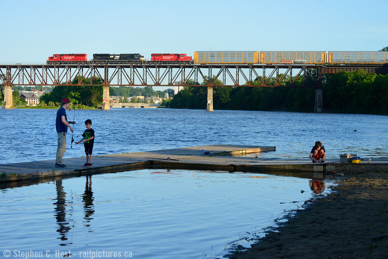 A father with his sons spending time fishing the Grand River while a train passes over downtown Galt on a cool summer evening.
Gotta love these summer evenings. My summer routine allows me a few nights to try my hand at a photo from the north side of River Bluffs Park in Galt -  Bill Miller turned me on to this spot a few years ago and normally a couple trains was easy, four was a good night. Now if you get one, you are doing well - things really have changed on the 'ol CP. This was my fourth attempt this season, and my first getting a train before the sun sets for good. With this in hand any evening photography I do in August 2017 will have to be elsewhere - this sure is a keeper.