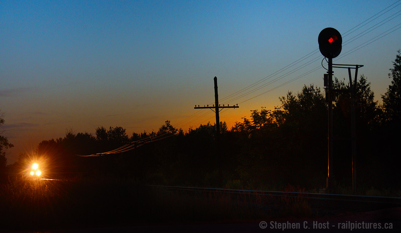 Frogs and crickets sing into the still and cool summer evening air, signalling the coming of darkness; the horizon glows orange with a midsummer's sun playing hide and seek until morning. It's 9:41 PM and a lone sentinel glows red to indicate the pending passage of a train on the CPR. In moments the frogs and crickets go silent as a rumble of EMD motive power grows closer, and a K3 horn blows in the distance. Codeline glows orange from headlights and my anticipation grows. EMD locomotives throb ever louder as T69's hogger pours it on to get to track speed, 60 mph, and your heart begins to beat faster. This stretch of track between the curves at Killean and Puslinch may as well be a racetrack, the stories from decades past, of trains making up time are the things of legend. Modern electronics and GPS forbid overspeed trains today, but the show never disappoints. To come will be part two of this small story.