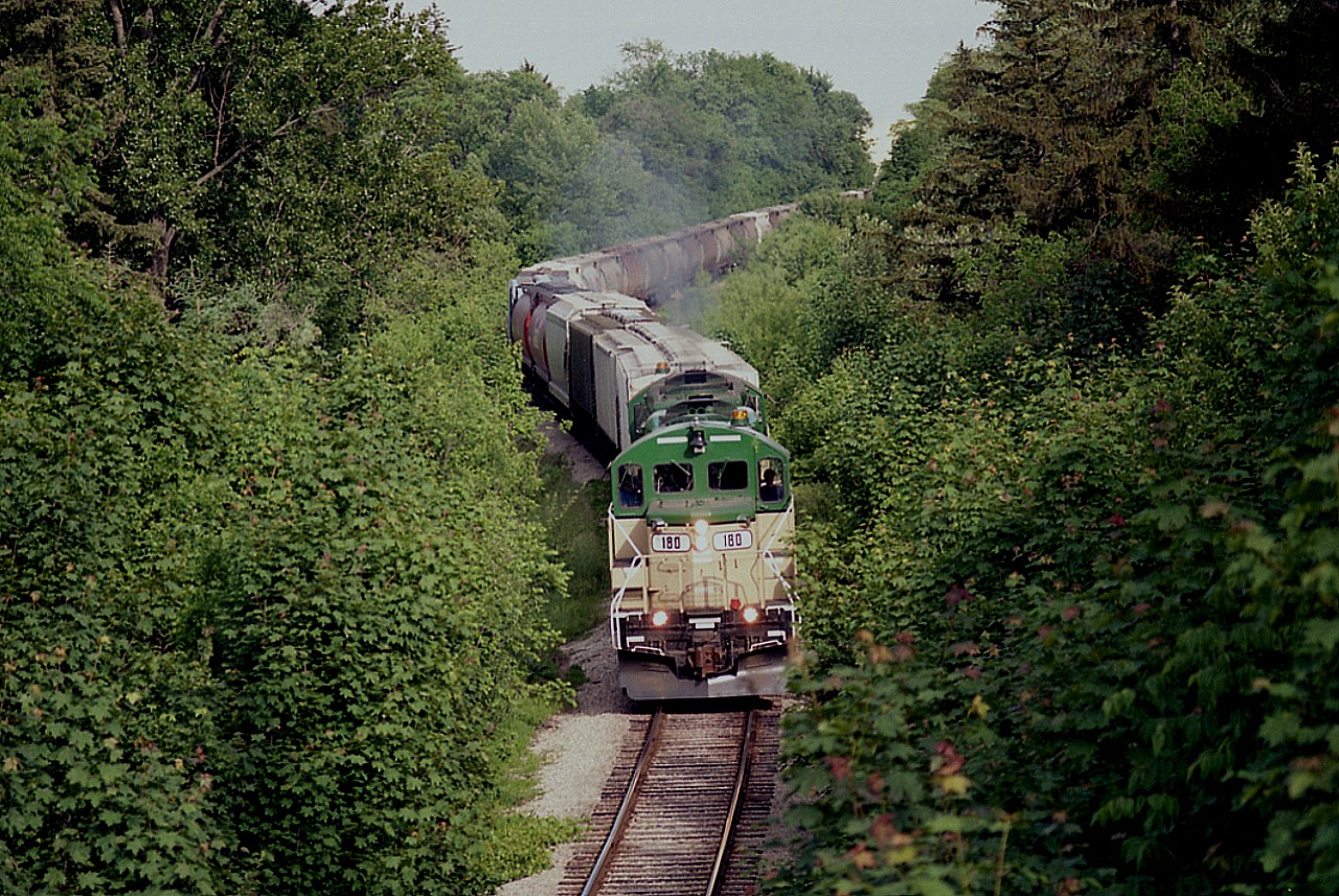 The fledgling GEXR had just completed its first 2 months of operations at the time this photo was taken. The view is of empties northbound to Goderich as seen from the bridge spanning the track on Avondale Av, NW part of town. Since the entire roster consisted of 4 identical GP9s, you pretty well knew what the power would be. :o) Sometimes they ran with three, but usually 2 locomotives and about a 20-25 car train. Loads were Sifto Salt (in season) bound for Ontario centres as well as Quebec, and Thompson Grain and Seed out of Seaforth (birdseed!) was another busy customer as well as Champion Road Graders in Goderich. There was enough business that the start up of 8 GEXR employees handled 7200 car loads the first year of operation; more than CN had the last years they operated the line. Sifto was especially pleased they could balance out their shipping a lot better, GEXR offered 5 day a week service as opposed to CN's 3. RailTex, the owner in the first years, offered at the time unique learning process for the non-union employees. They were trained in all positions from errand boy to engineer to office manager. Transportation specialists, I think they were called. I'm glad I managed the images along this line when I did, for all of us know whatever is powering a railroad today just may not be there tomorrow.