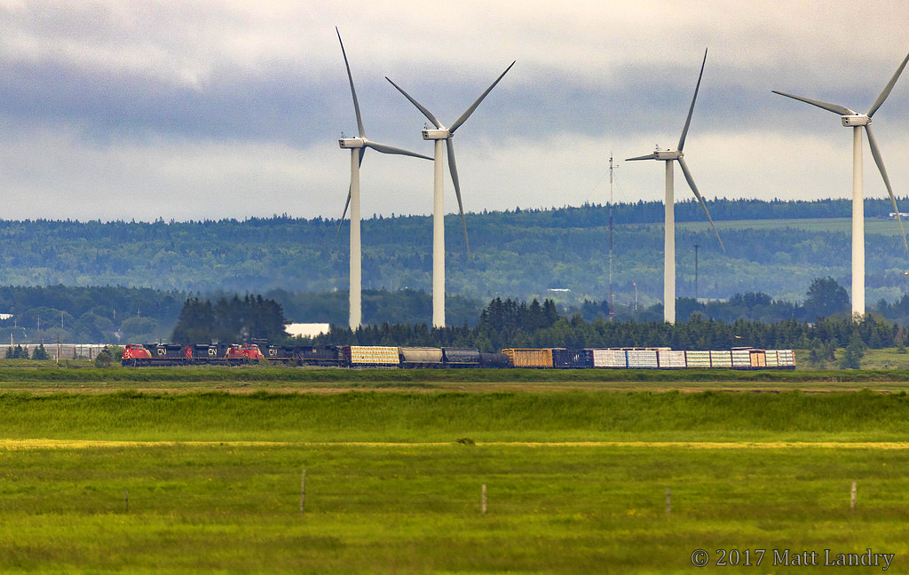 Taken with my 150-600mm lens, from Sackville, New Brunswick, CN 407 is seen rounding the bend at Fort Beausejour, New Brunswick, about 5 miles away, passing the turbines, which, in reality, are actually in Nova Scotia, as the train is crossing over the border.