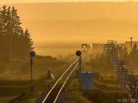 With a nice yellow sunset, eastbound train 408 rounds the bend, as they approach the New Brunswick/Nova Scotia border, and the approach signal to Amherst, Nova Scotia. 