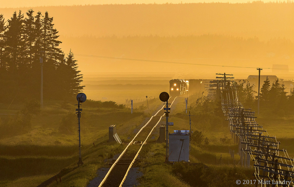 With a nice yellow sunset, eastbound train 408 rounds the bend, as they approach the New Brunswick/Nova Scotia border, and the approach signal to Amherst, Nova Scotia.