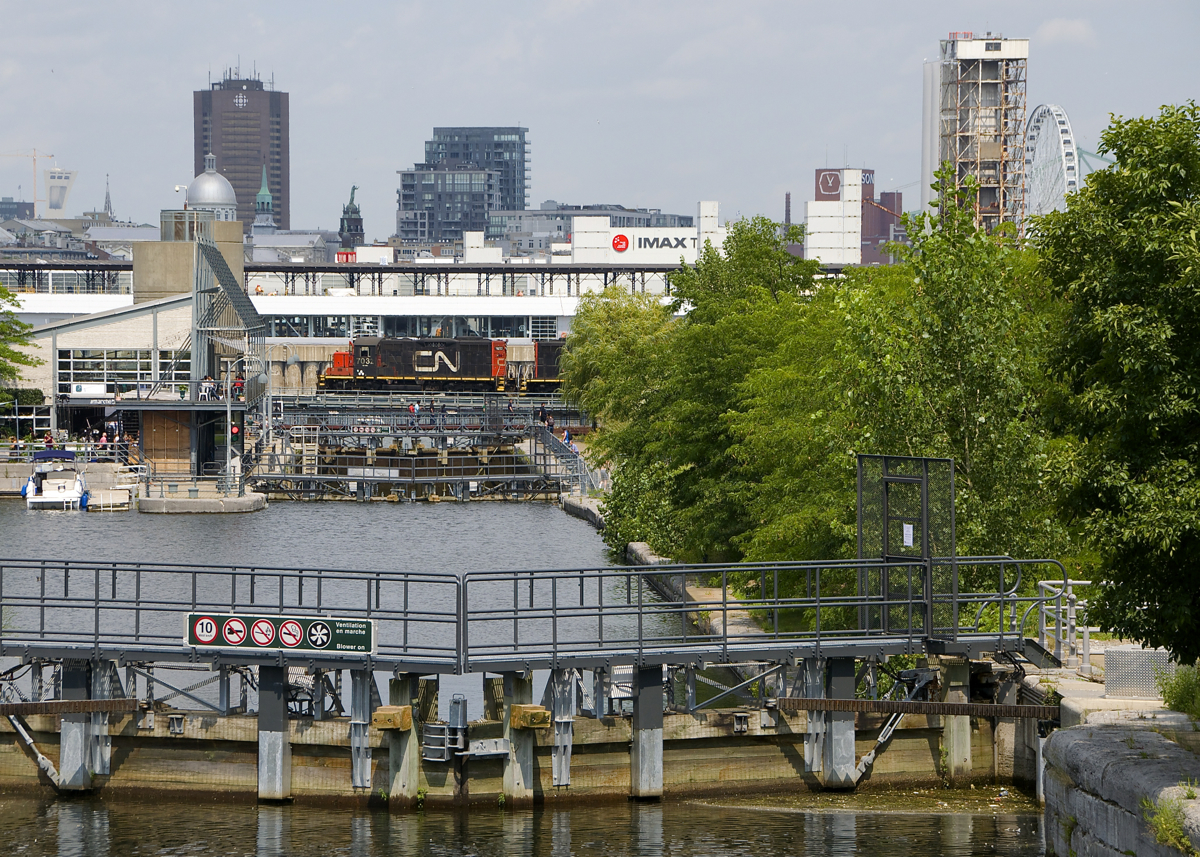 CN 7032 is stopped over the eastern end of the Lachine Canal before backing up with a cut of grain cars. In the foreground are a set of locks, used by pleasure boats on the canal.