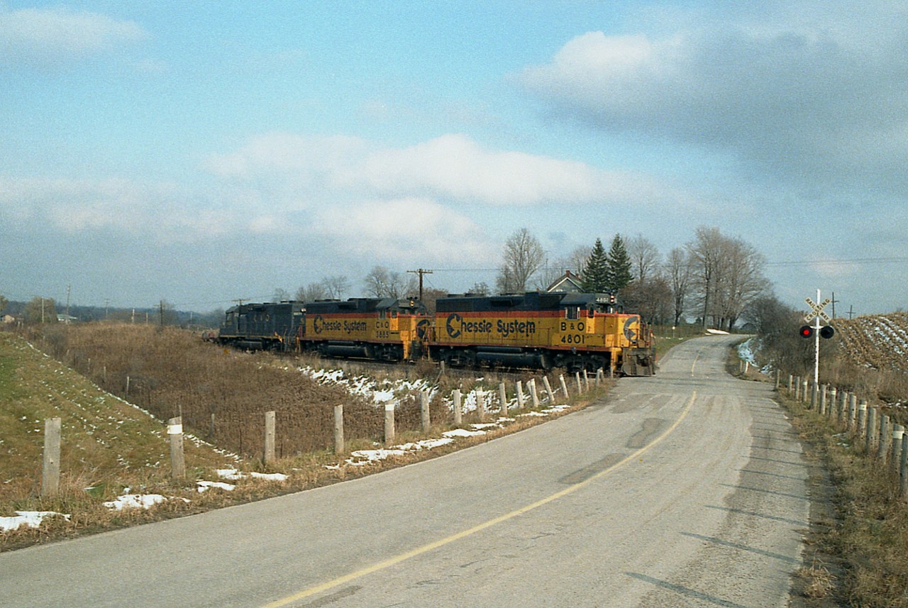 Starting into only the second week of the Nanticoke Steel train running over the TH&B down to Lake Erie (rather than over CN), we see B&O 4801, C&O 3885 and 4828 the power this time around. The train is just entering the Old Hwy 99 crossing. It is only about 1500 hours, a great day for following this train yet hardly anyone around. Today this is part of the Hamilton-Brantford Rail Trail. A wash-out in Brantford a long time back spelt the demise of this line.