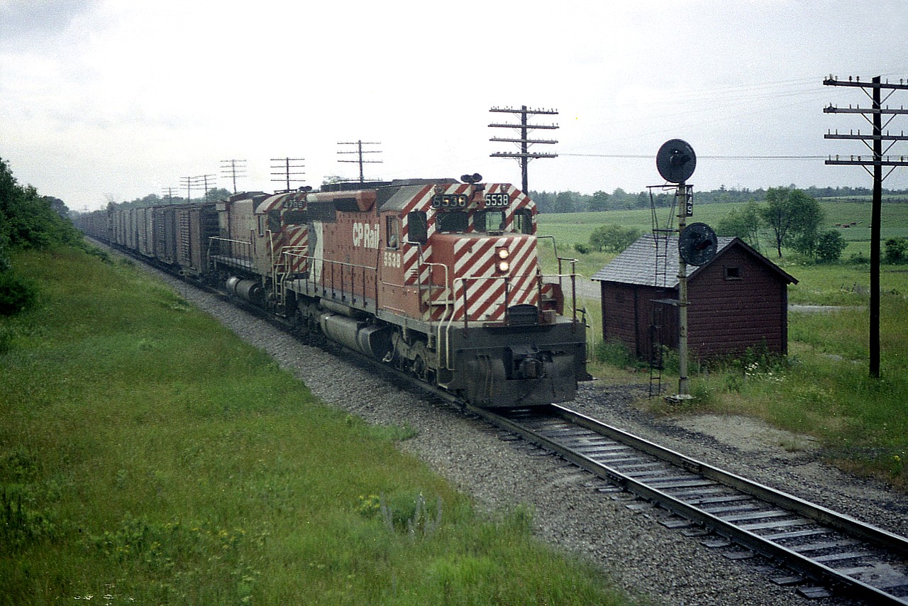 For those who know this area, the CP mainline looking westward at the eastbound train off the side of the Hwy 6 overpass in Puslinch, is one peaceful green scene back in 1976. Now, the area is over-run with farm equipment buildings and anything else country commercial. This shot is definitely worthy of a time machine effort. In this view we see CP 5538 and 4706 with a long long string of boxcars.......something else we see little of any more. Pity it was a dreary day, but it was a day off work, and back then the weather was a minor hindrance.