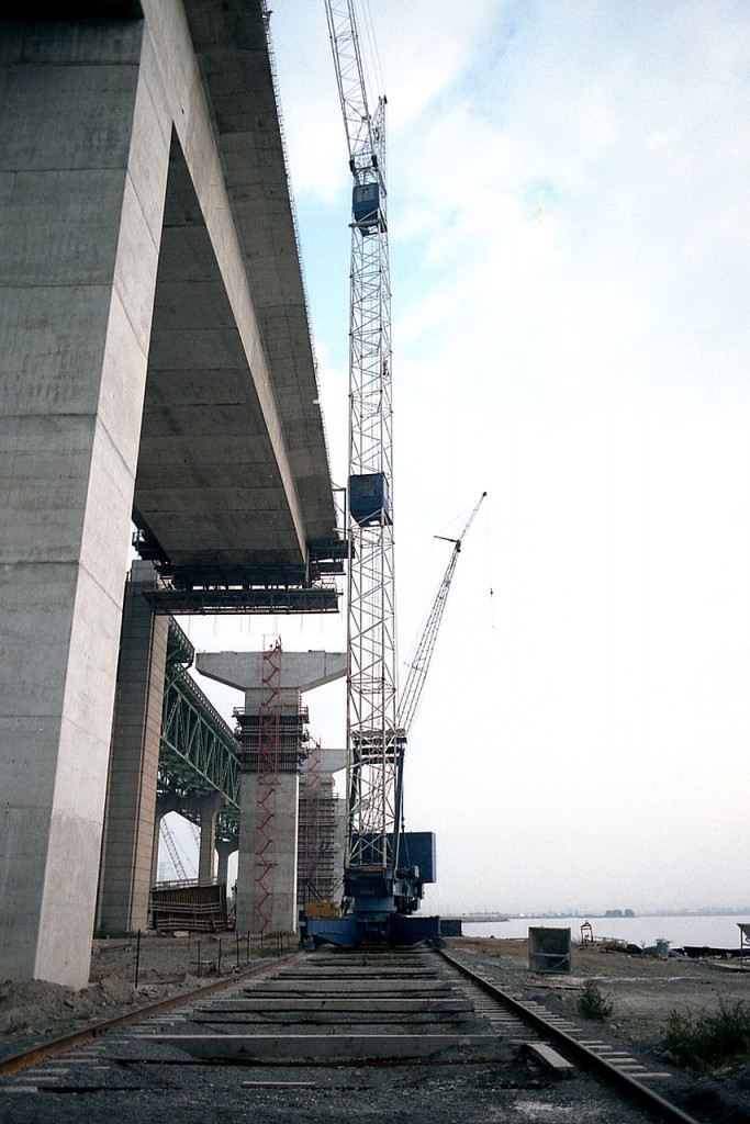 Looking down the wide gauge southward at the Skyway Railroad (yes, I am making this up) we see sole motive power 'Industrial Crane" assisting on the superstructure for the new Skyway bridge on the Burlington Beach strip back in 1984. At the time the original bridge was beginning to get congested, hence the demand for a twinning structure. Now what? It is just over 30 years later and both bridges are jammed with traffic most days. What do we do? There really isn't any room for a third. This was an ingenious way of having a tall crane make the 'rounds' though. After all, the beach strip is all sand. And I daresay this image qualifies as a 'railroad' scene. :o)