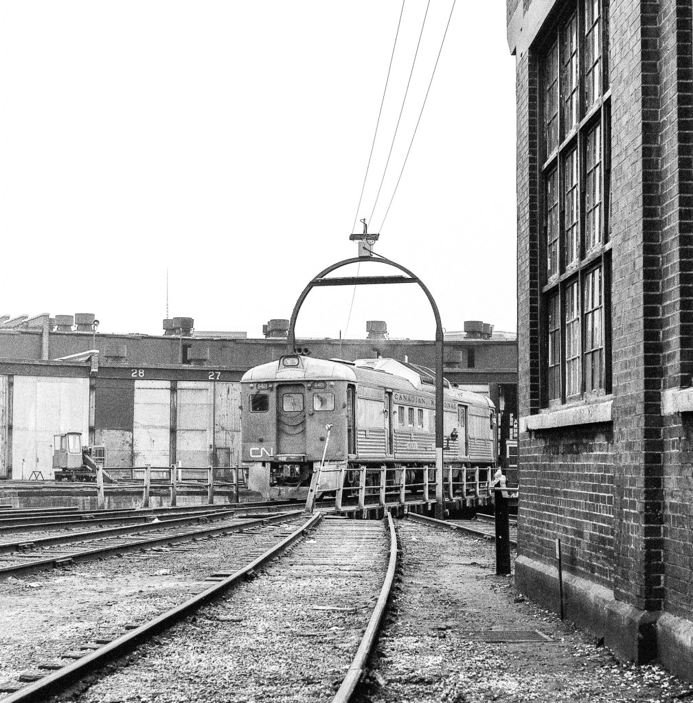 CN 6401 rides the turntable outside the CN roundhouse at Spadina yard in Toronto on a wet day in the late 1960's/early 1970's.