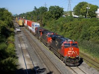 CN 120 (with CN 2893, CN 2658 & CN 2956 up front and CN 2858 mid-train) is exiting Taschereau Yard on the freight track, just as the tail end of CN 149 passes on the north track. The south track is also occupied, with a hi-railer stopped.
