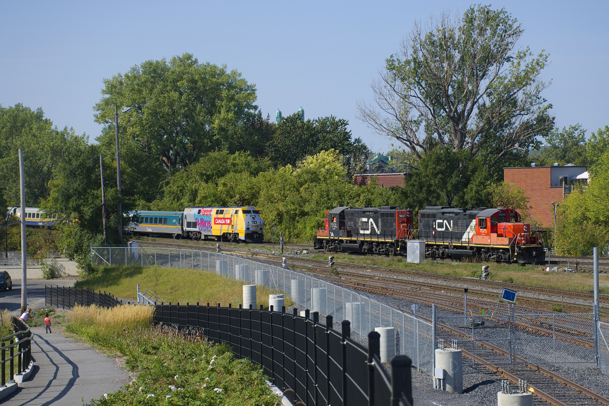 VIA 60 has P42DC class leader VIA 900 as it approaches a pair of stopped GP9's (CN 7032 & CN 7075) at the western end of Pointe St-Charles Yard. At left is the new railfans park.