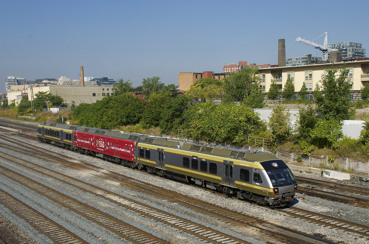A Union Pearson Express shuttle train is nearly at Union Station in downtown Toronto, en route from Toronto Pearson International Airport. The middle car is a 'wrap' sponsored by the CIBC bank celebrating Canada's 150th anniversary.