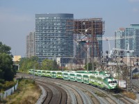 GOT 653 is passing under a number of searchlight signals as it pushes a 12-car train, with a stopped GO train behind it.