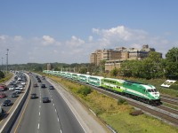 A GO Transit eastbound has a car in the new paint scheme at each end, with ten cars in between in the old scheme, as it approaches a pedestrian overpass at MP 4 of the Oakville Sub with GOT 620 leading.