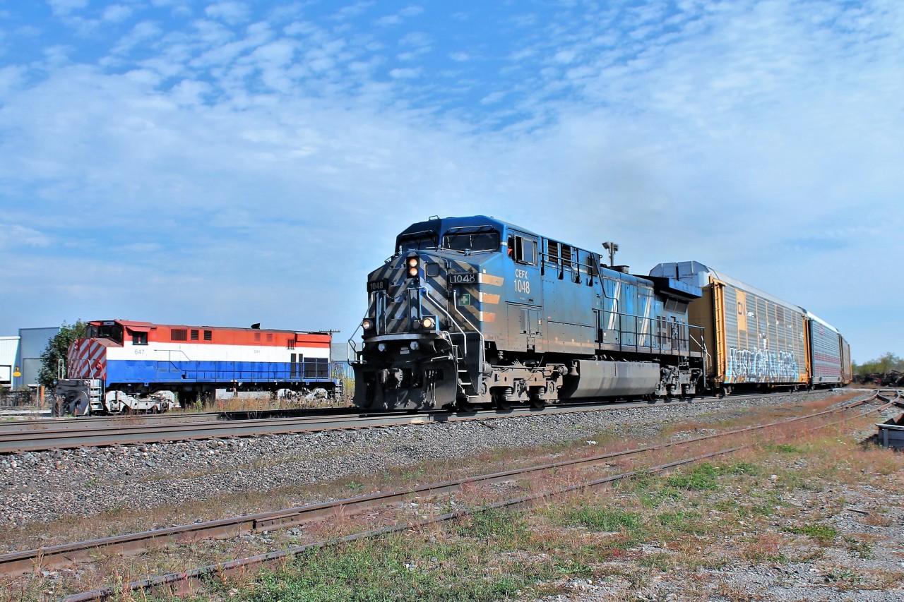 A lone CEFX 1048 slowly climbs the grade with this near 9600 foot auto rack train on its way through Guelph Junction as it passes by OSRX 647 parked in a siding.