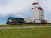 Grain empties from the UP at Kingsgate BC bound for Glenwood MN passes the grain elevator lettered Dog River for the sitcom Corner Gas which was filmed on location here