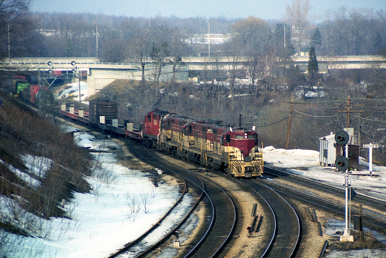 Back to the Junction. This image shows the overall view from the hillside where Mr. Host shot 25 years later, as recently posted. This was a favourite angle for a long time, until the No Trespassing signs went up down below and the parking area was lost. It is still a nice view, however most fans are content with the walkbridge a bit east of this location.
Late afternoon light, 'sweet-light' some call it, is rather evident on this old scene as the daily 'Starlite' from Toronto to Hamilton (and return) rolls thru behind TH&B 71, 401, 74 and CP 8778. I logged 56 cars and CP caboose 434554. Note the old line, some of it anyway, on the left that pushers from Steam Era days used to utilize, assisting trains up the long grade to Copetown. By the late 70's the siding/stub was just for MoW purposes. The switch is still in and the dwarf signal in place. The "Bayview" sign is still an old wooden one, rather than metal. Lots of changes.  Ah, the good old days........:o)