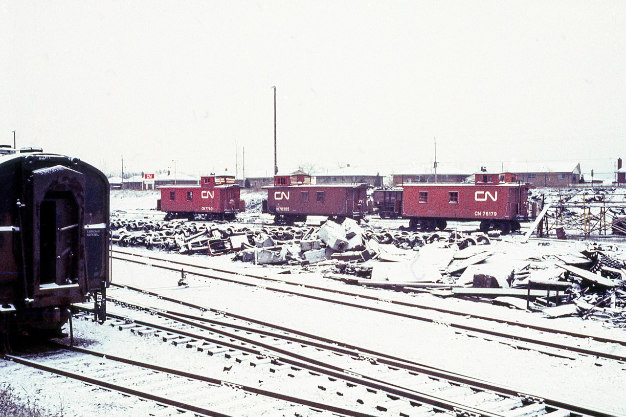 It was a cold and cloudy Saturday at the end of November 1968, and John Woodworth, Mike Ondecker, and I had driven to London, Ontario from Akron, Ohio. We had heard that there were CLC C-Liners in a scrap yard there. Much to our surprise there was nobody to ask for permission, so I took my photos, and we left. These three CN Vans standing alone by themselves and awaiting the scrapper's torch still provide a haunting memory to me. 
At a later date I might post some other photos taken there on that day.
As I was new to slide photography this isn't my best quality, but it certainly brings back memories.