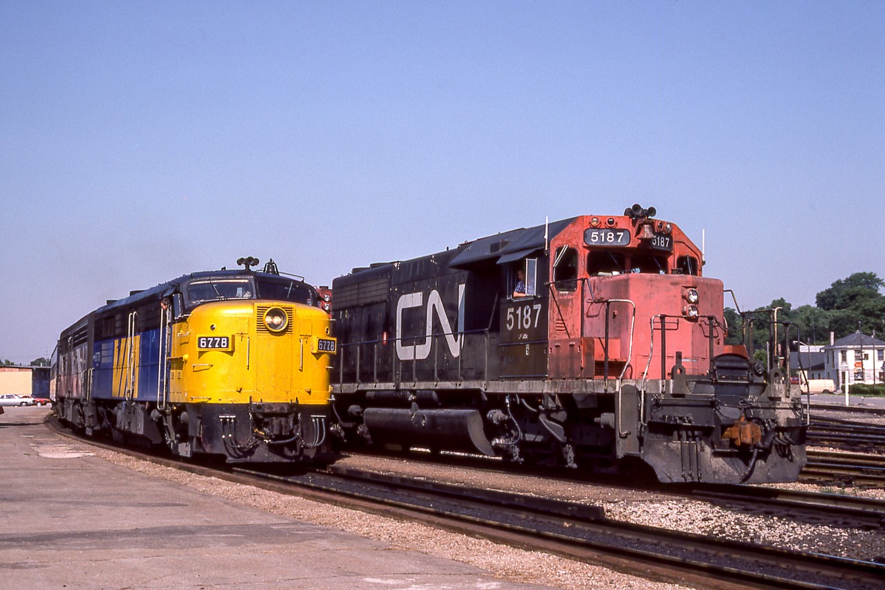VIA 6778 is making a station stop while CN 5187 sits next to the passenger train.