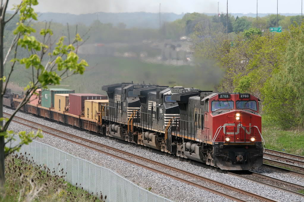 A Tuesday after a holiday weekend....eastbound 148 with a pair of NS GE's trailing. This pic was easy..out the front door..up the hill...point and shoot. Not sure why they needed a fence built when the tracks were separated by a large berm. Highway 403 in the background