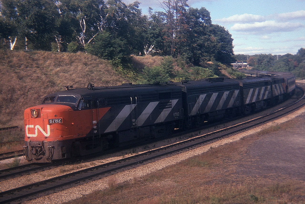 A weekend CN passenger #75 is just coming off the CN Oakville Sub onto the Dundas, heading west in this late afternoon image. It is a real shame I cannot find my notes, so the only ID I have is the CN 6782 leader. This looks to be a long train, and the A-B-B-A power is impressive. Note in the far background that this is PRE-walkbridge, that is the old access bridge to the Snake Rd back there. It was replaced by the modern walkbridge in 1975.