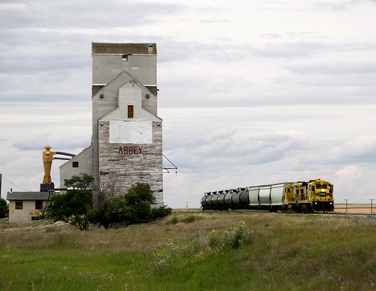 CP Spinoff Great Sandhills Railway with leased ex ATSF GE's rolls past the station that tops the Canadian Gazetteer alphabetic station list. Tank cars are either taken out of storage of loads from Empress Gas Plant south of Leader