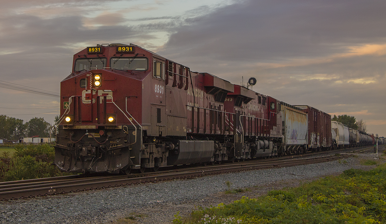 Early mornings can equal great opportunities. The weather was perfect. The sun was just starting to rise, but there was still enough cloud cover that it illuminated the sky. Keeping myself occupied, with time to kill before work I was driving around hoping for a break. I came across the tracks by the ethanol plant, and to the west I saw a trio of eastbound headlights coming my way. With no time to spare I pulled into CP's access path, put the car in park and hopped out with camera in my hand. At this point, the crossing lights had been triggered, and the gates were lowering so I knew I had very little time to setup for this shot. Despite the lack of time, I was able to snag this shot of CP 8931 & 8943 passing the sidings at Bloomfield Road on it's approach into Chatham.