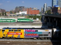 Wrapped VIA 905 pushes VIA 73 towards Union Station in Toronto. Behind is the GO North Bathurst Yard where numerous trainsets wait out the middle of the day and at right is the Spadina overpass.