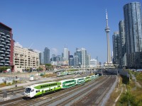 Cab car GOT 319 leads a GO Transit westbound out of the flyunder as it approaches the Bathurst Street overpass. In the background is the North Bathurst yard and behind that is the skyline of downtown Toronto.