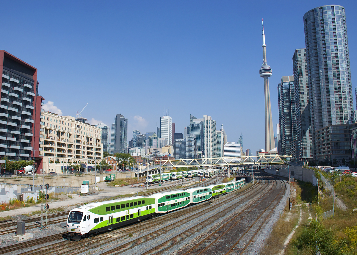 Cab car GOT 319 leads a GO Transit westbound out of the flyunder as it approaches the Bathurst Street overpass. In the background is the North Bathurst yard and behind that is the skyline of downtown Toronto.