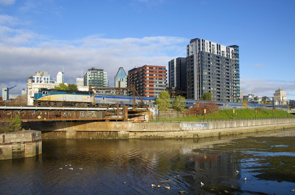 VIA 63 has VIA 6413 leading the usual seven stainless steel coaches as it crosses the Lachine Canal and passes Wellington Tower.