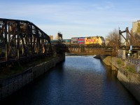 VIA 906 leads VIA 69 over the Lachine Canal, with the out of use swing bridge formerly used by CN freights to access the Port of Montreal locked in position at left.