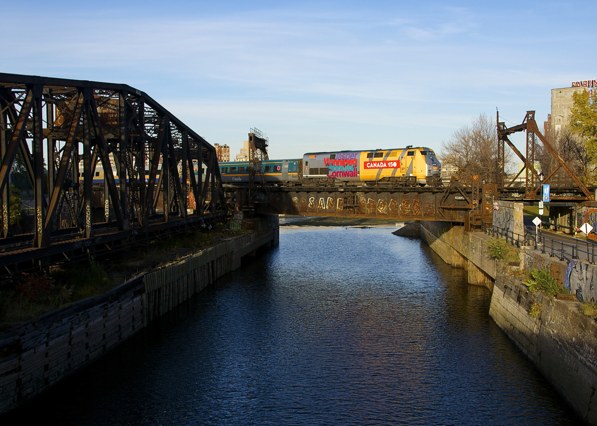 VIA 906 leads VIA 69 over the Lachine Canal, with the out of use swing bridge formerly used by CN freights to access the Port of Montreal locked in position at left.