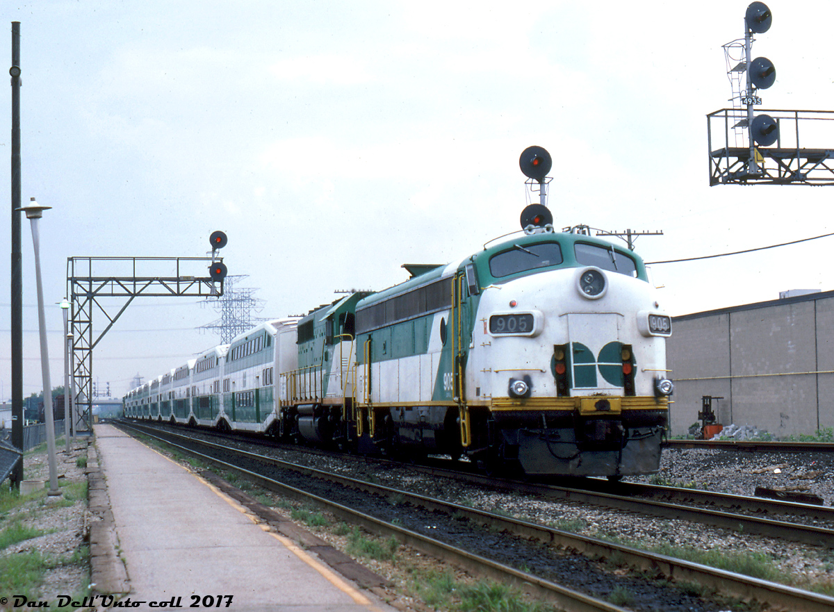 Looking back today, exciting was a word one could use for a certain era of GO Transit - but at the time it was probably all ho-hum to the regulars trackside. Such is life I suppose.

GO APCU 905 trails a westbound train of 10 bilevels with a GP40 sandwiching each end, rolling through Burlington Station on August 21st 1986. GO's small fleet of APCU (Auxiliary Power Control Units) were rebuilt from old Ontario Northland and Milwaukee Road FP7's that got a second reprieve at life. They were needed to both act as cab control cars for the expanding fleet, and to provide Head End Power electricity to the coaches that GO's roster of GP40-2W and GP40-2 rebuilds couldn't provide. Upon the scads of new F59PH's arriving on the scene in the late 80's/early 90's, GO's rag-tag fleet of GP40's, F40's and F-unit rebuilds would be retired. While the 40's would go on in freight and passenger service with other roads, only two of the APCU/APU F-units survived, and the rest were stripped and cut up for scrap at Willowbrook in 1995.

Reg Button photo, Kodachrome from the Dan Dell'Unto collection.