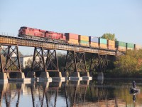 A lone fishermen pays no attention to the CP west bound stack train starting across the Trent river in the early morning sun light. common power on a common train by today's standards. Track work on the north set of rails east of the bridge this summer, Does CP have excess to the Cascade paper plant to the north?